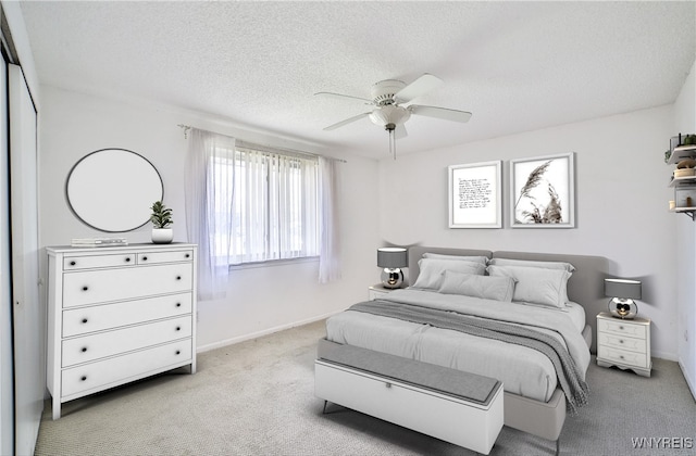carpeted bedroom featuring a textured ceiling, baseboards, and a ceiling fan
