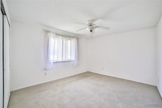 carpeted empty room featuring ceiling fan, a textured ceiling, and baseboards