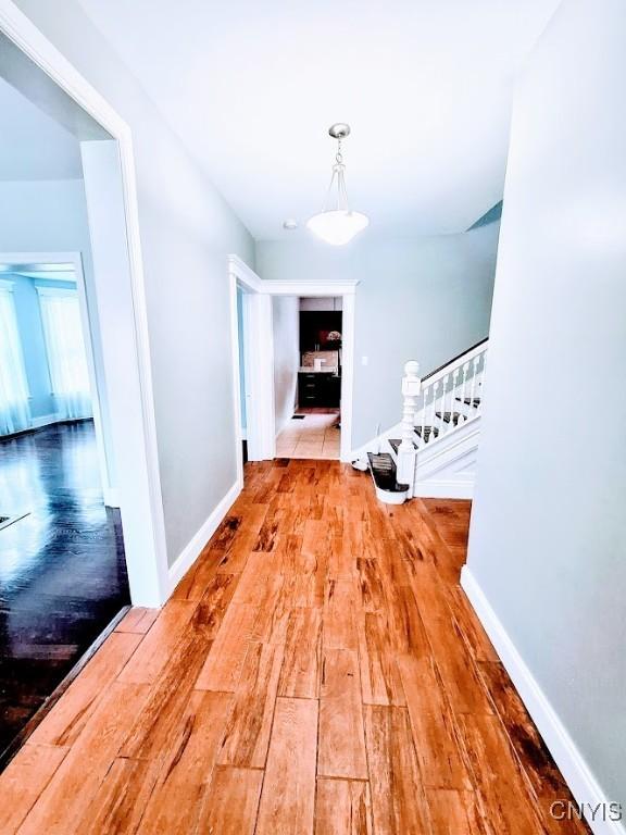hallway with stairway, wood finished floors, and baseboards