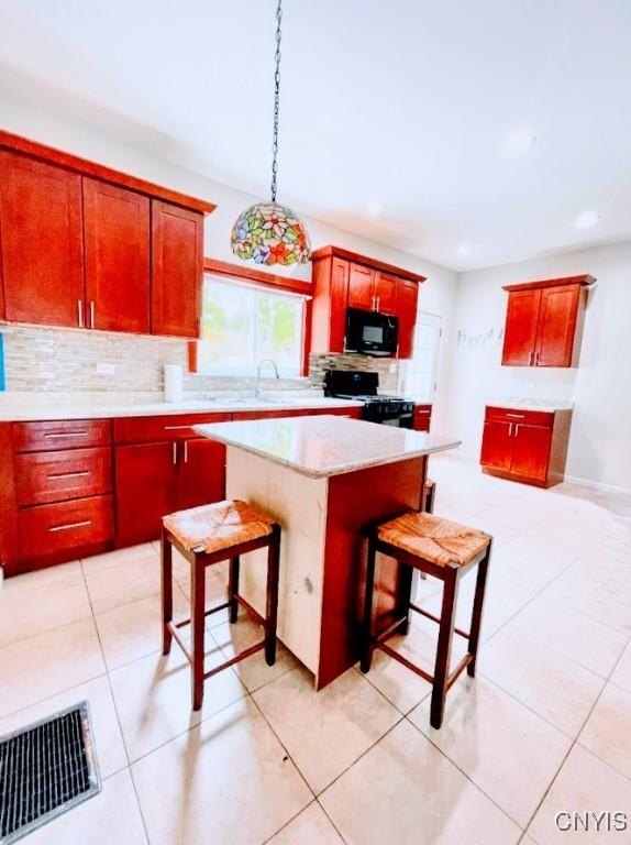 kitchen with black appliances, decorative backsplash, light countertops, a kitchen bar, and light tile patterned floors