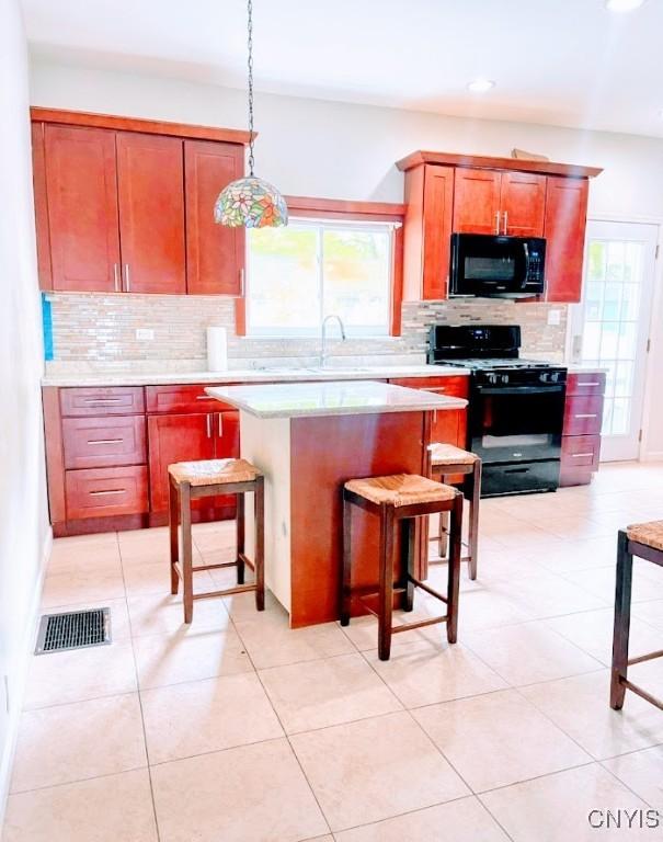 kitchen with black appliances, decorative backsplash, light countertops, a sink, and a center island