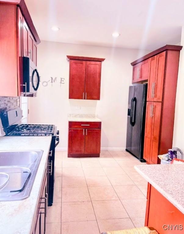 kitchen with black appliances, light countertops, baseboards, and light tile patterned floors