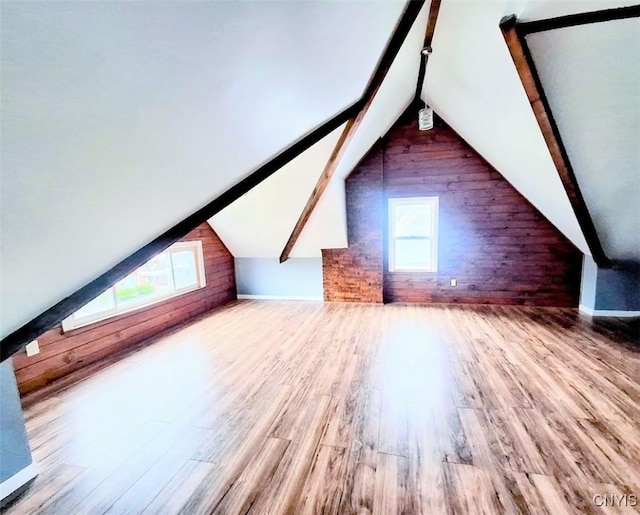 additional living space featuring healthy amount of natural light, wood finished floors, and wood walls