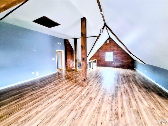 bonus room featuring wood finished floors, wooden walls, vaulted ceiling, and baseboards