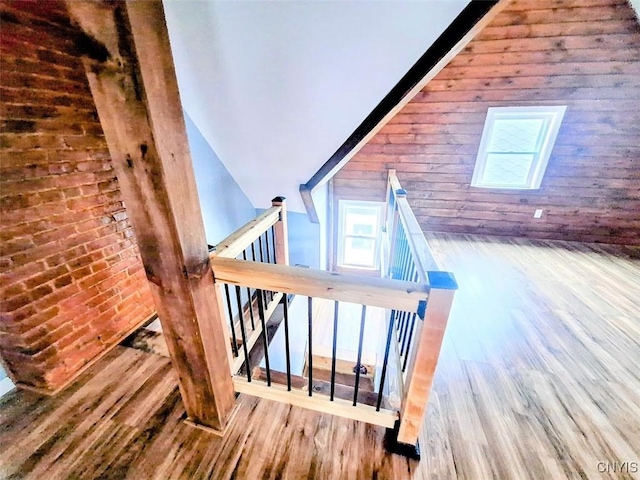 stairway featuring wood finished floors, wood walls, and a skylight