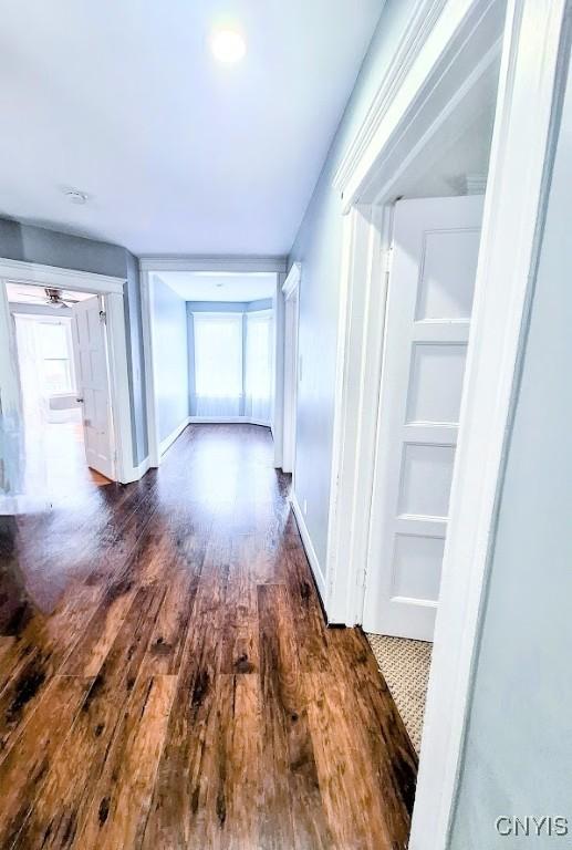 hall with dark wood-style flooring and baseboards