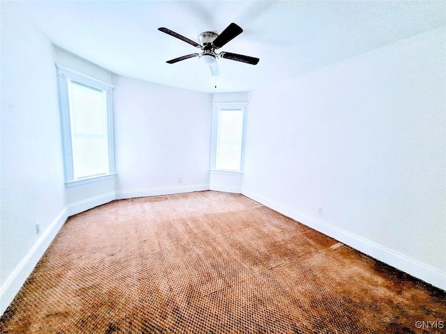 spare room with baseboards, light carpet, healthy amount of natural light, and a ceiling fan