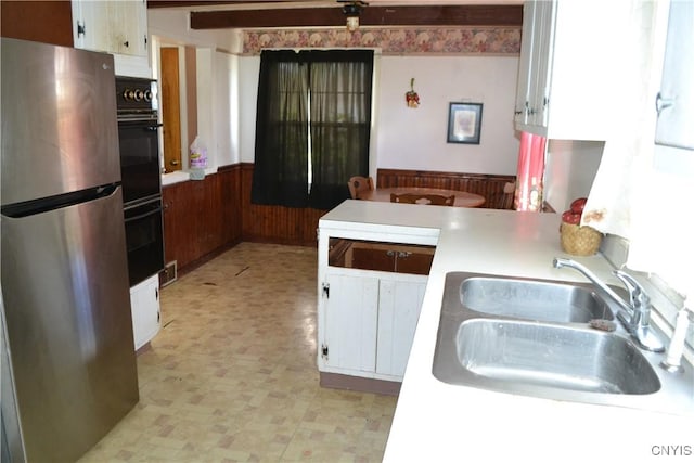 206 Marilyn Ave, Salina, NY 13212 - kitchen with freestanding refrigerator, a sink, wainscoting, light flooring, and white cabinetry