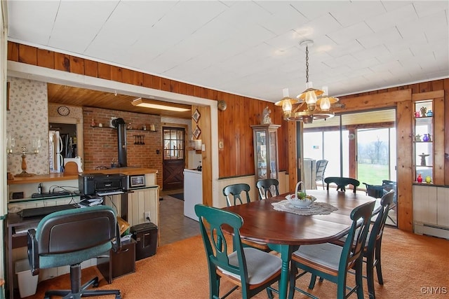 3542 Griffin Rd, Onondaga, NY 13215 - dining space featuring light carpet, wood walls, a chandelier, a wood stove, and a desk
