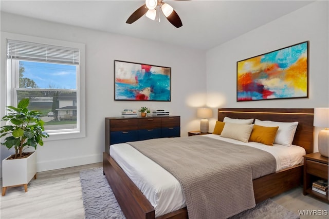 bedroom featuring baseboards, light wood-style flooring, and a ceiling fan