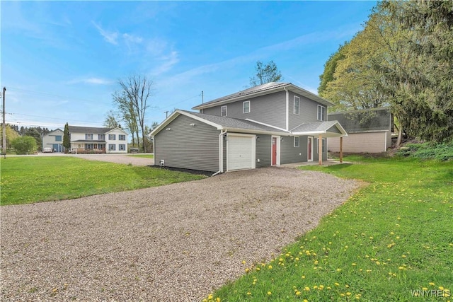 view of front of house featuring a garage, gravel driveway, and a front lawn