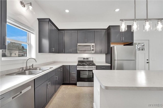 kitchen with stainless steel appliances, a sink, light countertops, recessed lighting, and pendant lighting