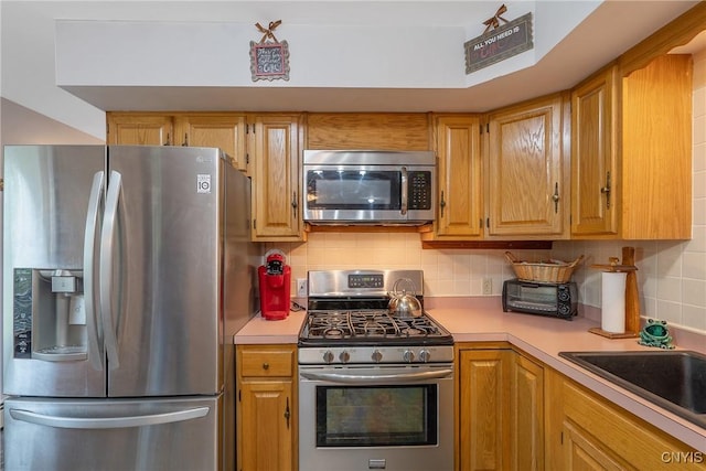 kitchen with appliances with stainless steel finishes, light countertops, and tasteful backsplash