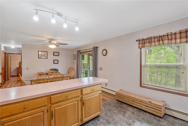 kitchen with ceiling fan, light countertops, baseboard heating, and wood finished floors