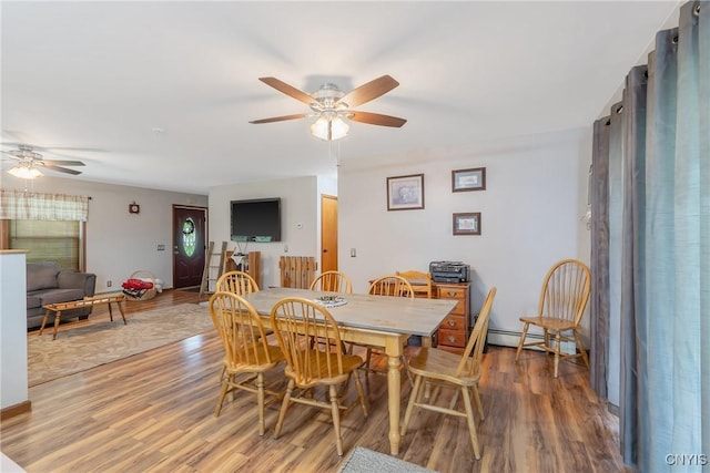 dining room with a ceiling fan, wood finished floors, and baseboard heating