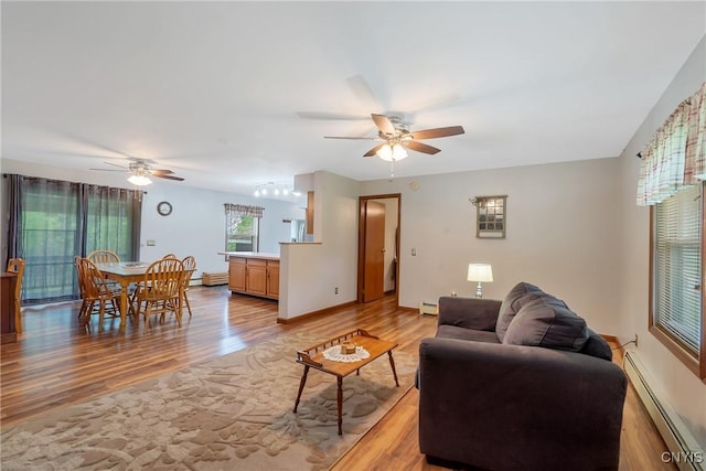 living area featuring a baseboard radiator, ceiling fan, and light wood-style floors