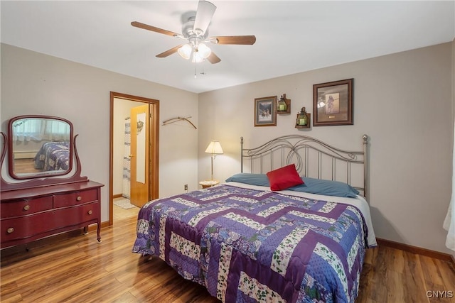 bedroom with wood finished floors, baseboards, a ceiling fan, and connected bathroom