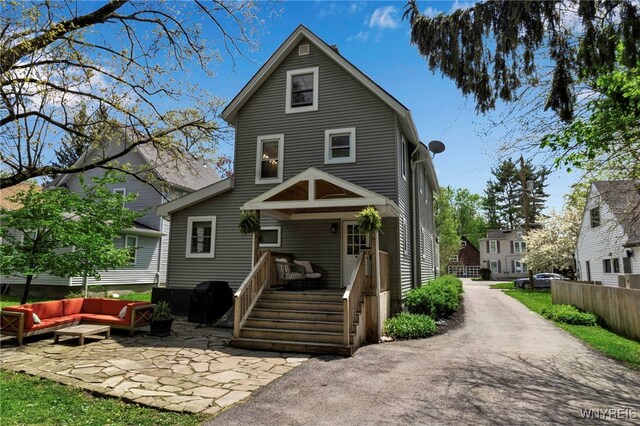 rear view of property featuring an outdoor living space and fence