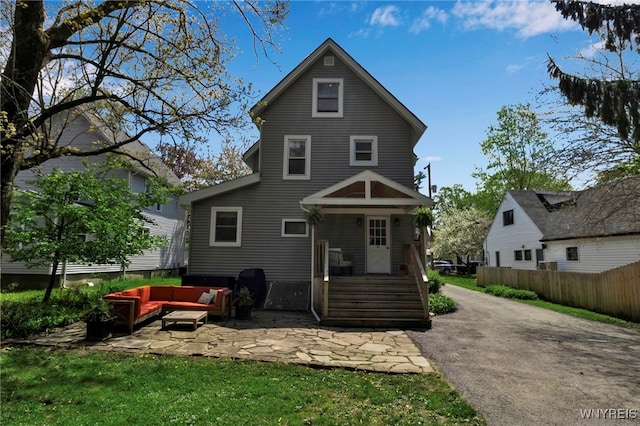 back of property with an outdoor hangout area, fence, and a patio area
