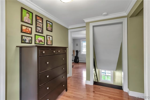 corridor featuring a baseboard radiator, light wood finished floors, ornamental molding, and baseboards