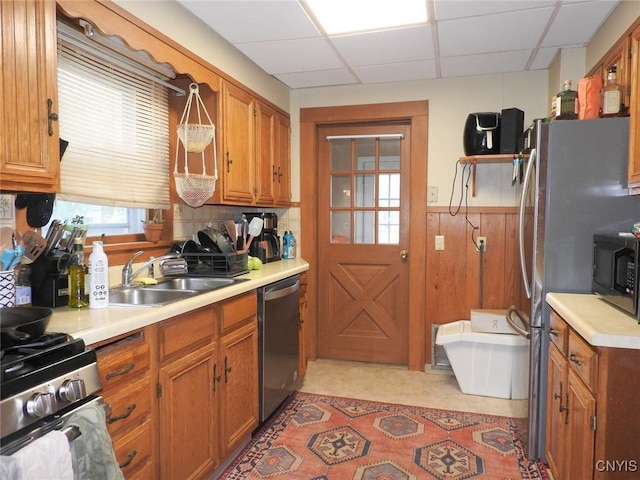 23 Paul St, Auburn, NY 13021 - kitchen featuring stainless steel appliances, a drop ceiling, brown cabinetry, light countertops, and a wainscoted wall