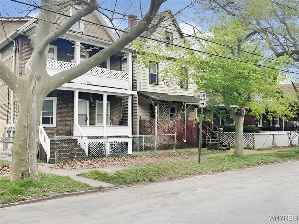view of side of home featuring a chimney, fence, and stairs