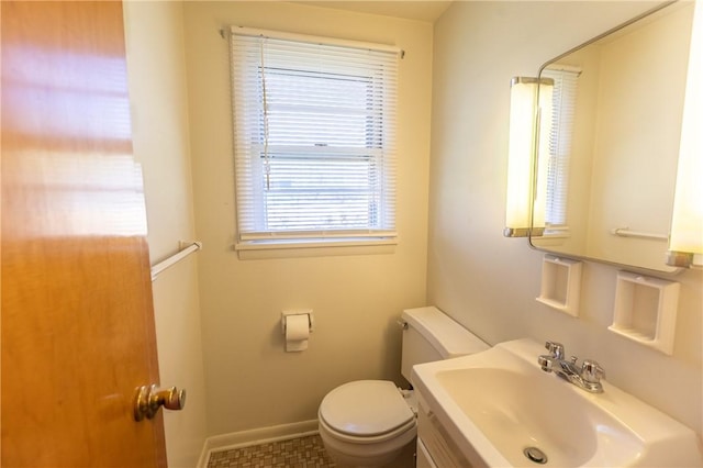 half bath with a sink, toilet, and baseboards