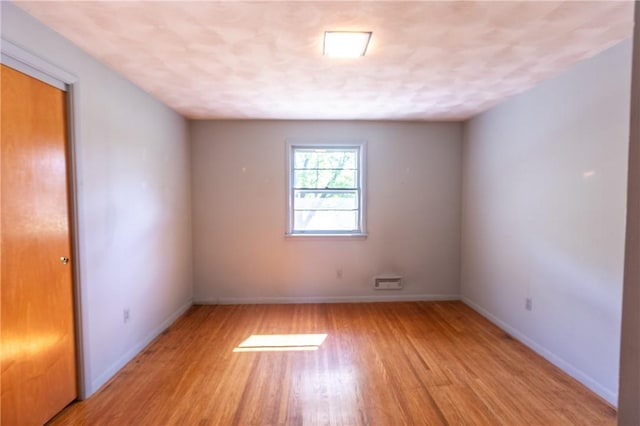 empty room featuring light wood-type flooring and baseboards