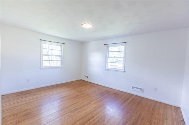 unfurnished room with plenty of natural light, light wood-style flooring, and baseboards