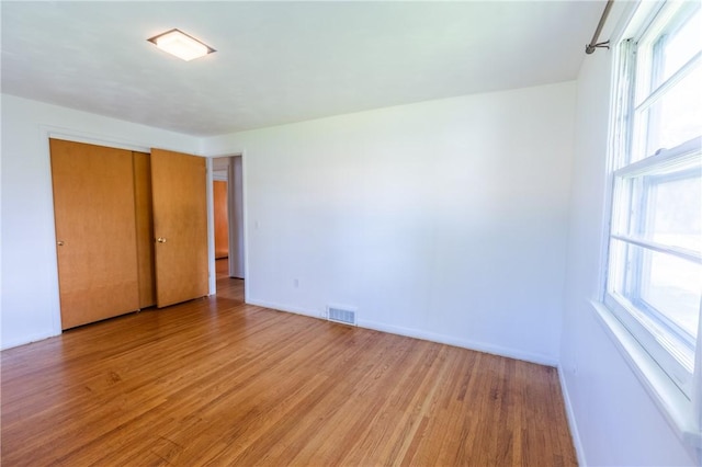 unfurnished bedroom featuring light wood-type flooring, baseboards, and a closet