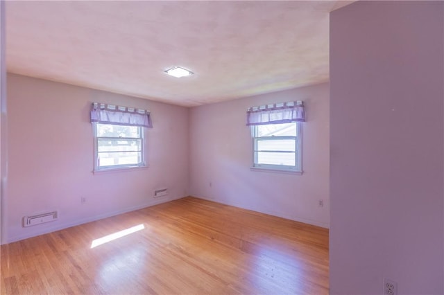 unfurnished room featuring plenty of natural light, light wood-style flooring, and baseboards