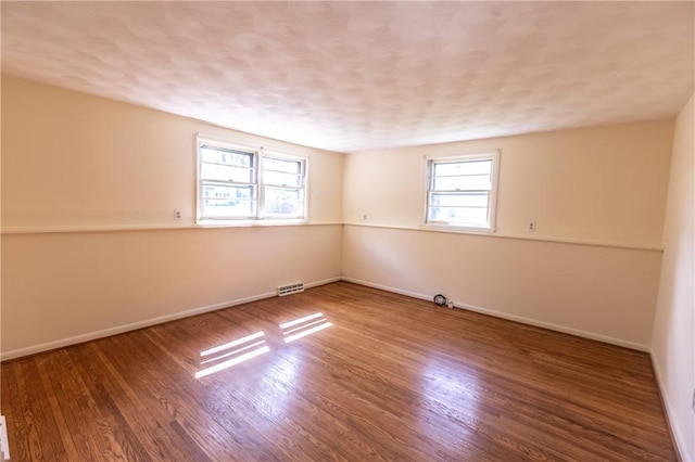 spare room featuring baseboards and wood finished floors