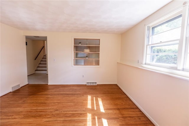 empty room with light wood finished floors, stairs, and baseboards