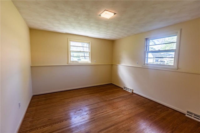 unfurnished room with plenty of natural light, wood finished floors, and baseboards