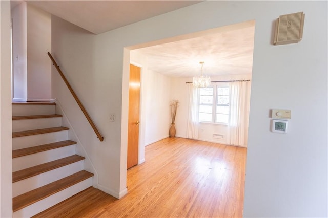 stairway featuring a chandelier, wood finished floors, and baseboards