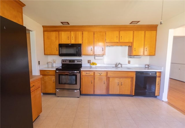 kitchen with black appliances, a sink, light countertops, and brown cabinetry