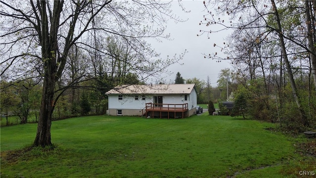 rear view of property featuring a wooden deck, a yard, and metal roof
