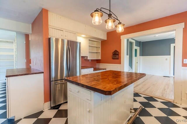 1957 Torpy Pond Rd, Georgetown, NY 13061 - kitchen with wood counters, freestanding refrigerator, light flooring, a wainscoted wall, and a center island