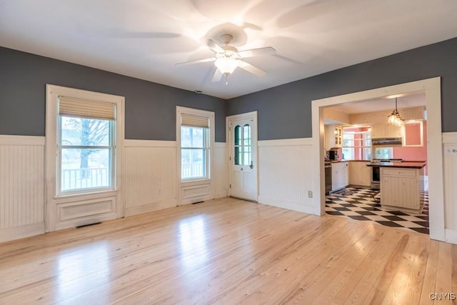 1957 Torpy Pond Rd, Georgetown, NY 13061 - unfurnished living room with a wainscoted wall, light wood-style flooring, and a ceiling fan