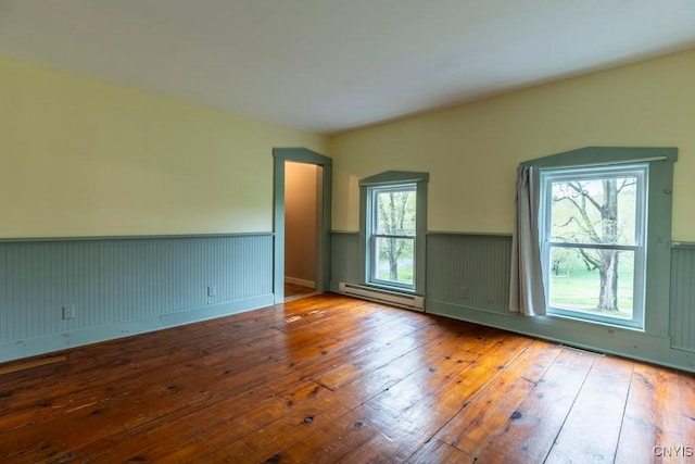 1957 Torpy Pond Rd, Georgetown, NY 13061 - empty room with a baseboard heating unit, a wainscoted wall, and hardwood / wood-style floors