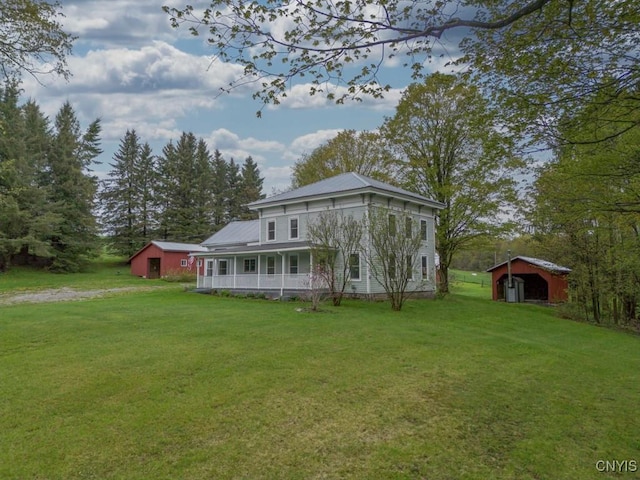 1957 Torpy Pond Rd, Georgetown, NY 13061 - view of front of house featuring a front lawn, an outbuilding, metal roof, and a porch