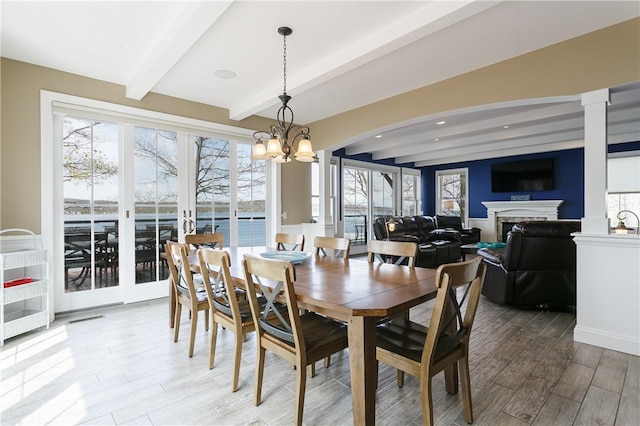 5088 E Lake Rd, Gorham, NY 14544 - dining room featuring beamed ceiling, wood finished floors, a chandelier, arched walkways, and a fireplace