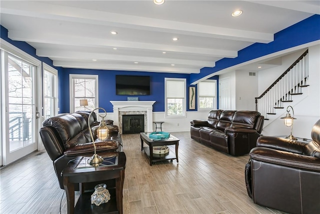 5088 E Lake Rd, Gorham, NY 14544 - living room featuring beamed ceiling, light wood-style floors, recessed lighting, a glass covered fireplace, and stairs