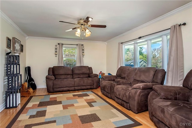 living room featuring light wood-style flooring, ceiling fan, ornamental molding, and baseboards