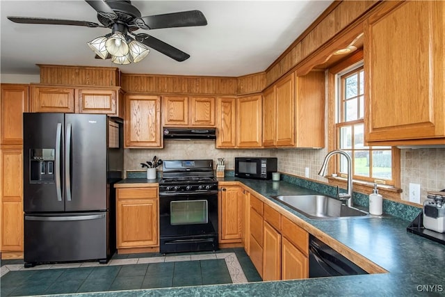 kitchen featuring black appliances, a sink, under cabinet range hood, decorative backsplash, and dark countertops