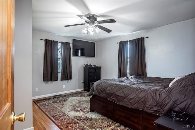 bedroom with wood finished floors, baseboards, and a ceiling fan