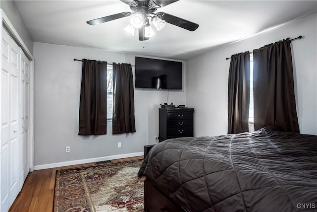 bedroom with wood finished floors, baseboards, a ceiling fan, and a closet