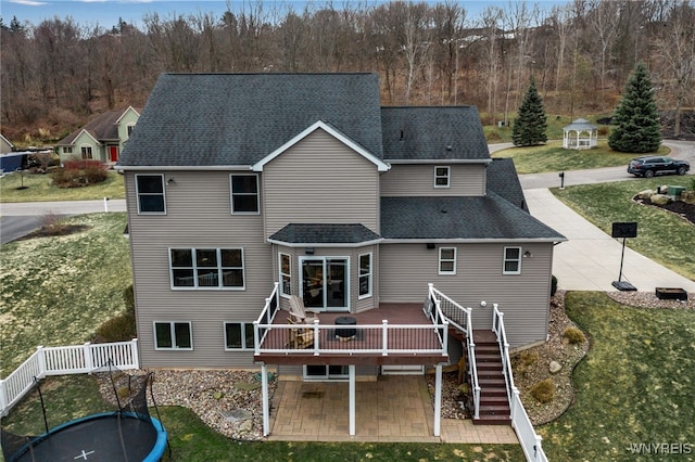rear view of property featuring a deck, stairs, roof with shingles, and a yard