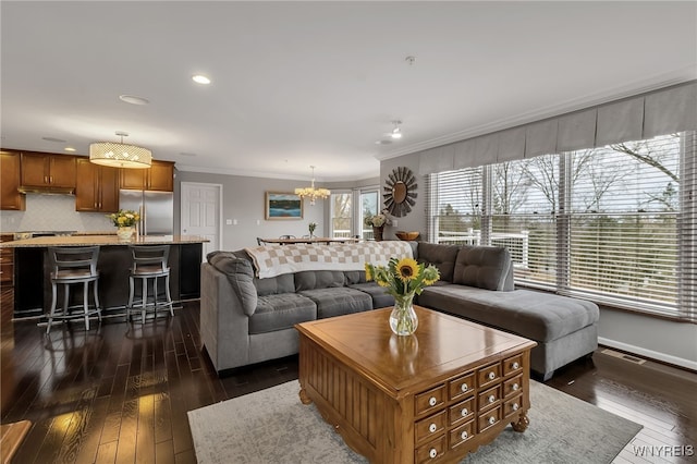 living area featuring a chandelier, dark wood-style flooring, crown molding, recessed lighting, and baseboards
