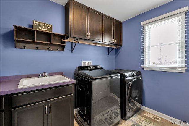 washroom with cabinet space, independent washer and dryer, healthy amount of natural light, and baseboards